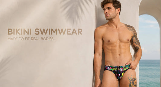 Adult male model wearing Gigo men’s bikini swimwear in a clean editorial beach setting, showing a confident fit, supportive pouch, smooth waistline and modern swim style.