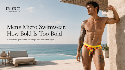 Male model wearing Gigo fruit print micro swim brief in a luxury beach resort setting, showing a bold low-rise swim fit with yellow waistband, drawstring detail and confident editorial styling.